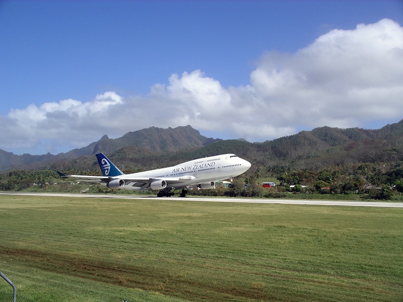 An aeroplane taking off on the runway with mountains and a blue sky in the background