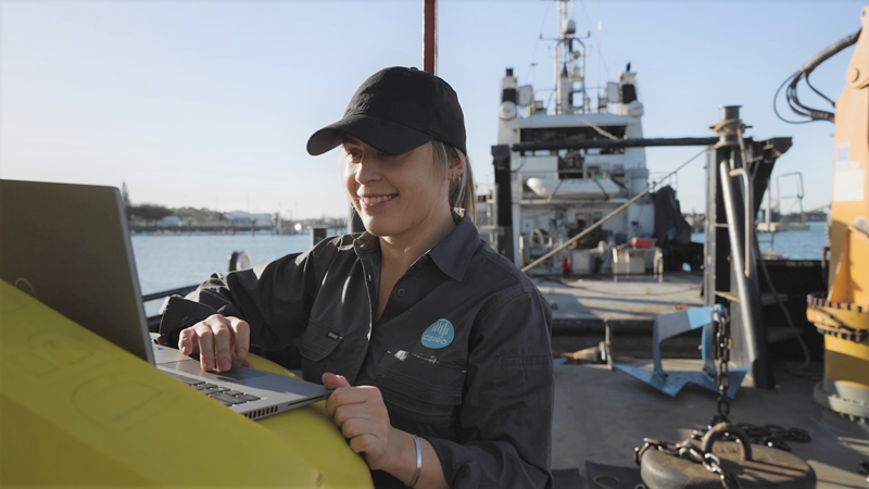 CSIRO scientist on a boat, reviews water quality data on laptop.