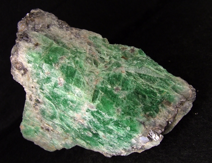 a grey rock with bright green crystal-like sections throughout