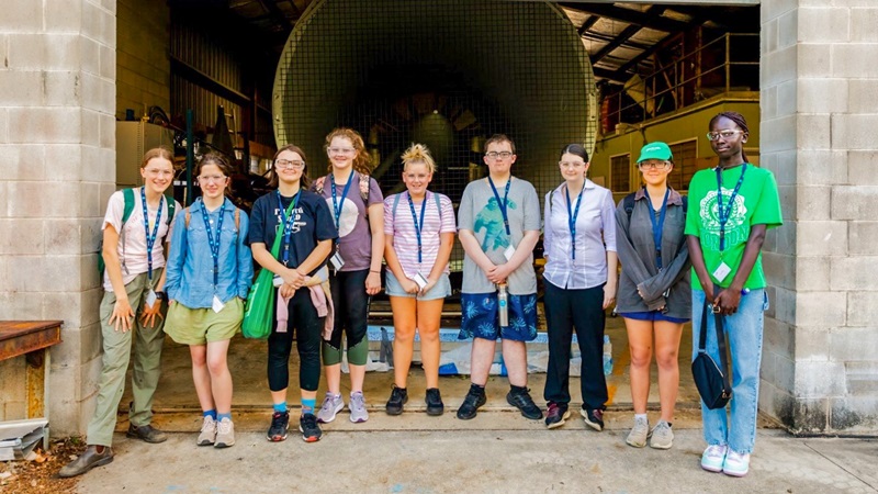 A group of students stand in front of a wind turbine at JCU’s cyclone testing facility