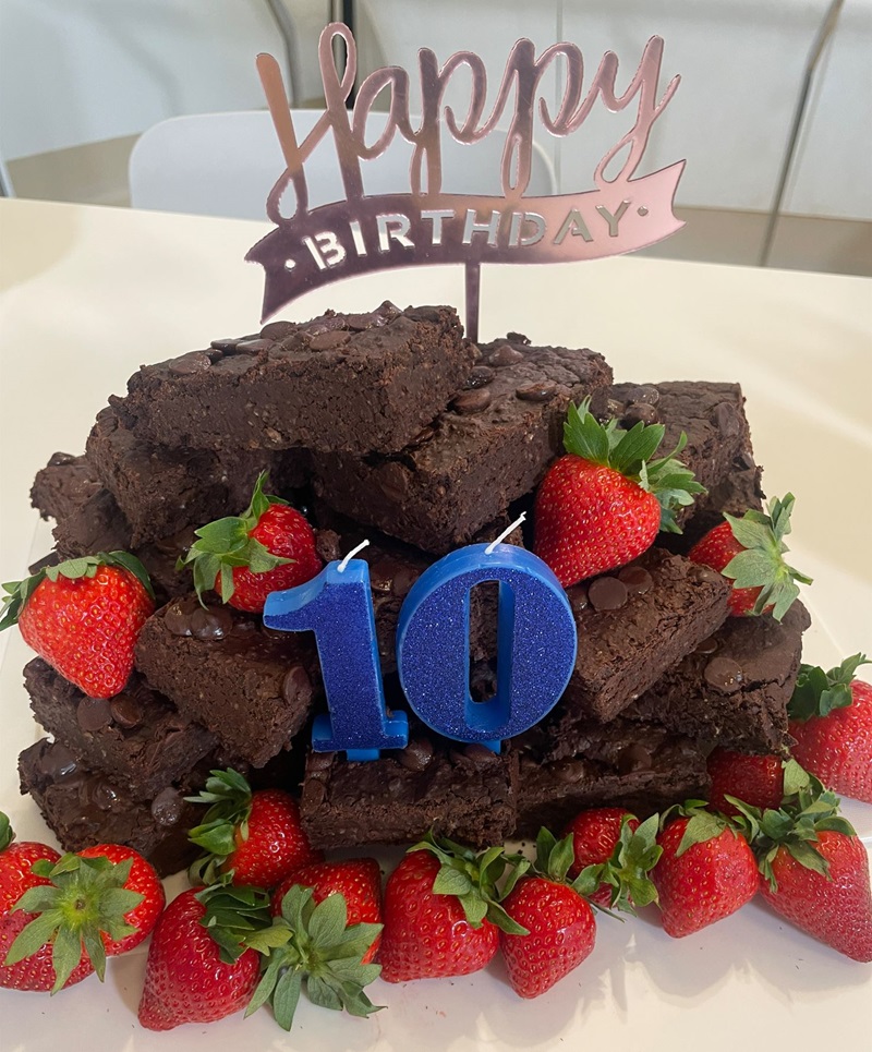A pile of brownies surrounded by strawberries. A small sign says happy birthday! and under that is the number 10. 