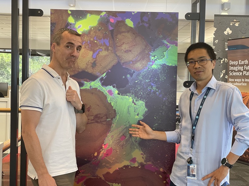 Two men looking quizzically at a coloured mineral characterisation picture
