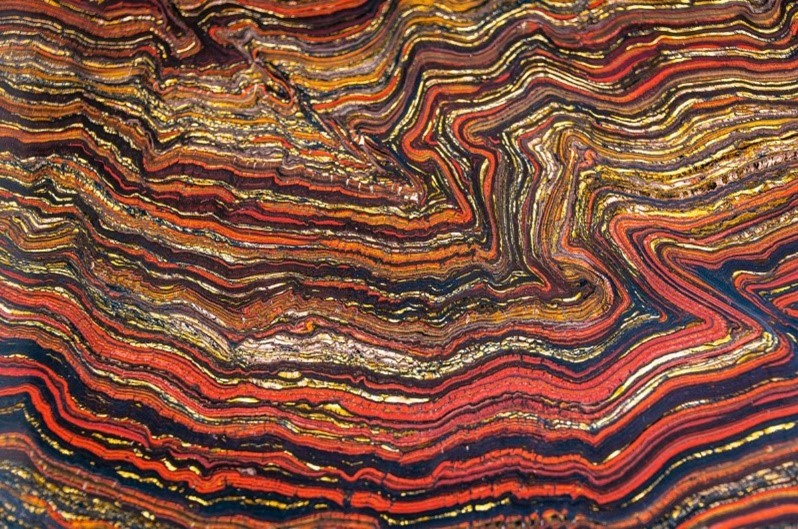 sedimentary rock in wavy lines of reds, oranges and browns