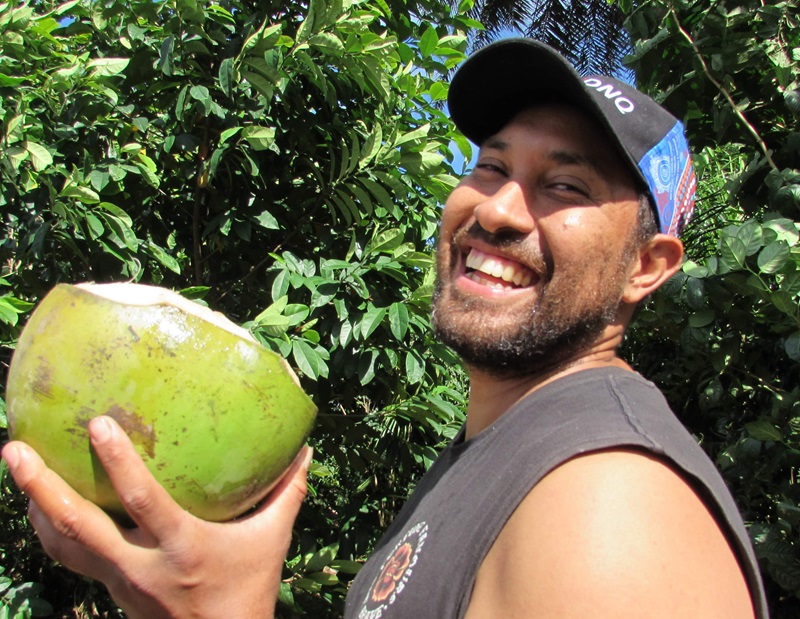 Headshot of Torres Webb smiling to camera holding a coconut