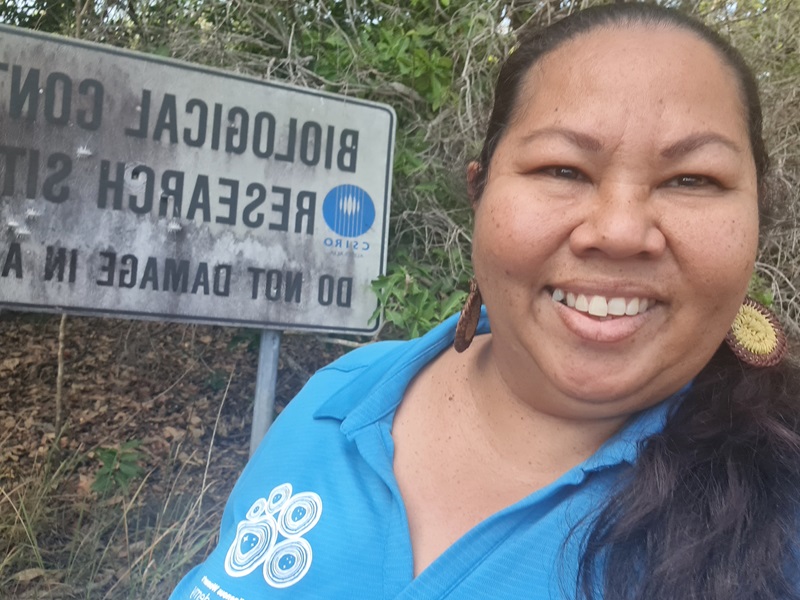 Woman smiles in front of sign at a farm property.