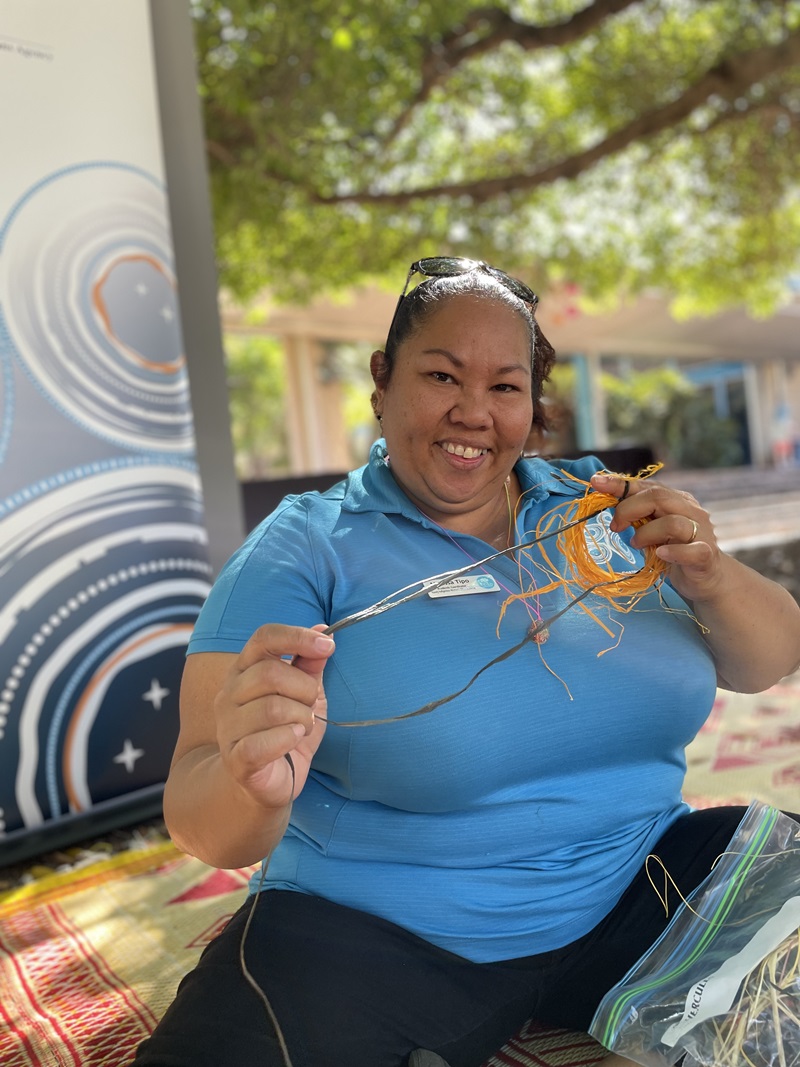 Woman sits showing traditional weaving craft.