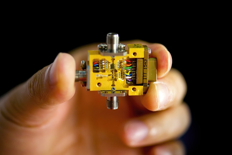 A hand holding a small gold device used in quantum technologies. 