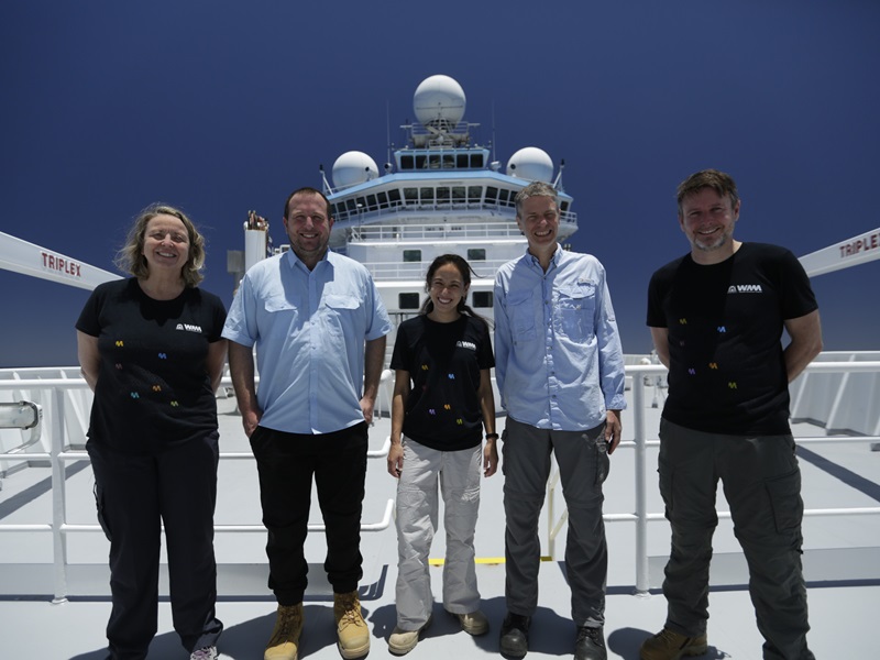 Five people standing on the deck of a ship.