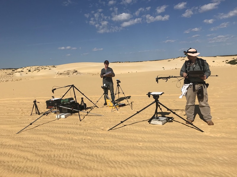 Two people with instruments in sandy desert