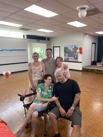 Group family photo with Dylan standing at the back with his arms around two family members, and two other family members seated in front.