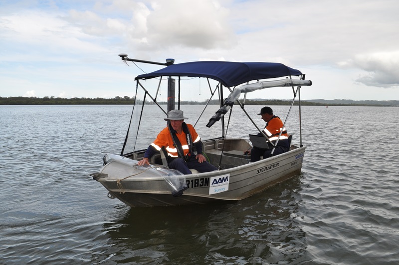 Smal 'tinny' boat with a cover and two people in high viz on a river taking measurements