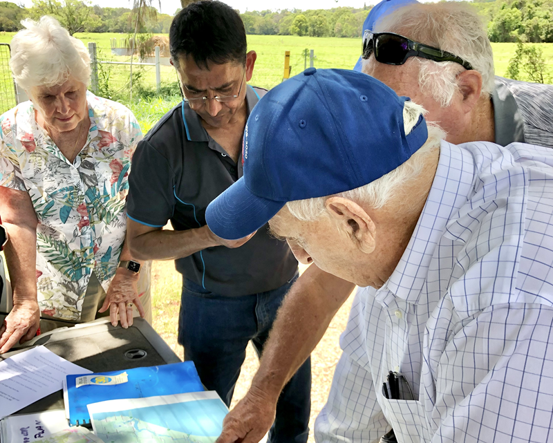 Dr Jai Vaze at a consultation session outdoors with 3 residents looking at documents on a table.