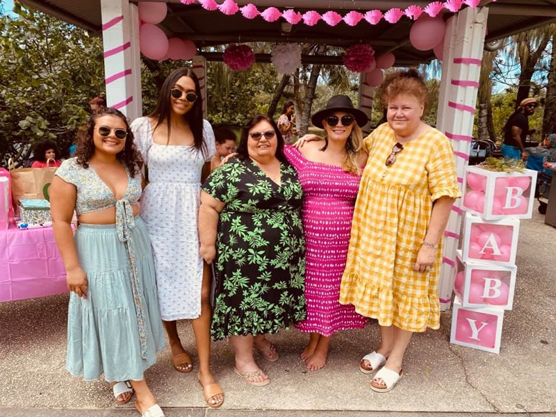 Sharnie with family members all wearing brightly coloured dresses at a family function.