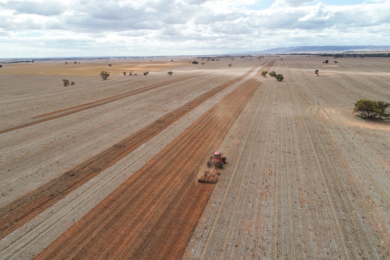 Aerial view of a tractor working across long red-brown strips of sandy soil at a trial site in Crystal Brook.