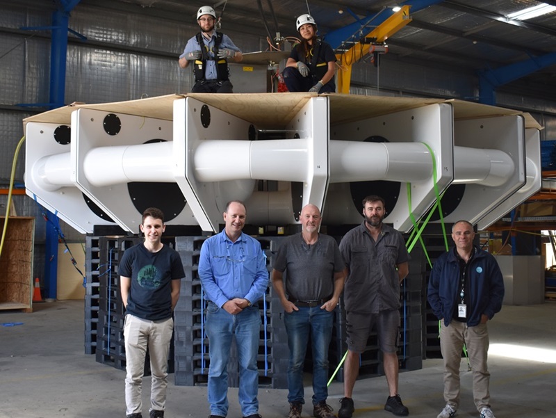 Group of people standing around massive ore sensor