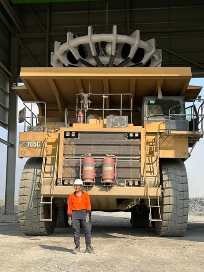 Mining truck with person standing in foreground