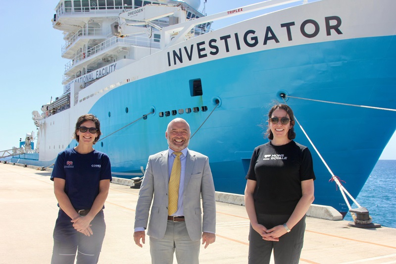 Three people standing in front of a ship.
