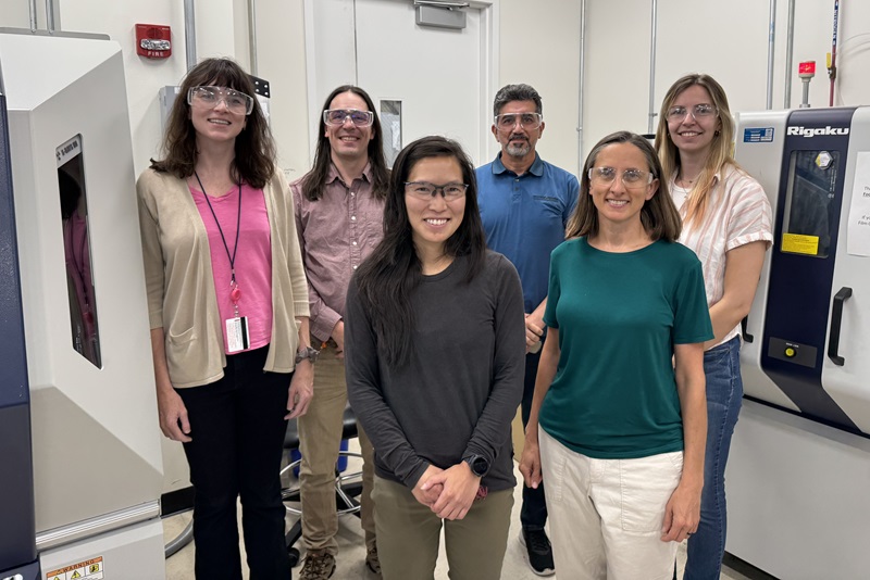 Six people in a small group in a lab facing the camera