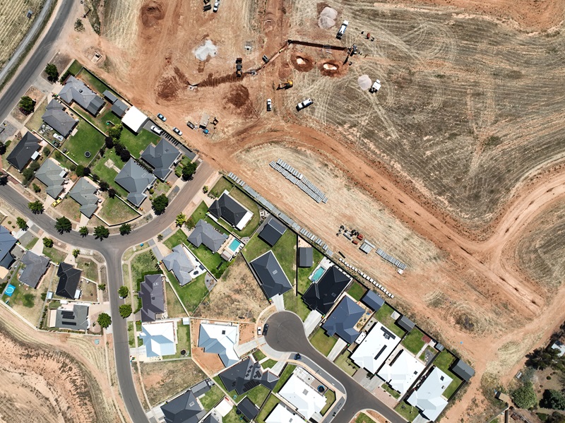 Drone footage of a new housing estate under development, adjacent to an existing suburb