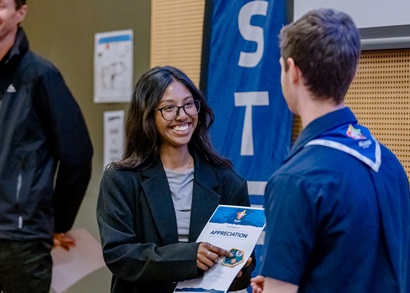 A female STEM professional accepts a certificate of acknowledgement from a Scout leader