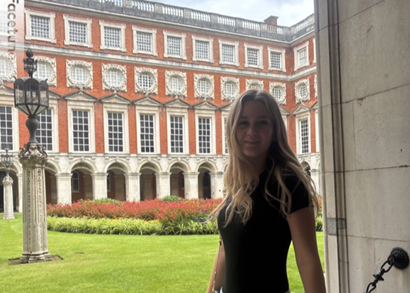 Person standing behind chained off area in front of part of Hampton Court Palace in London. 