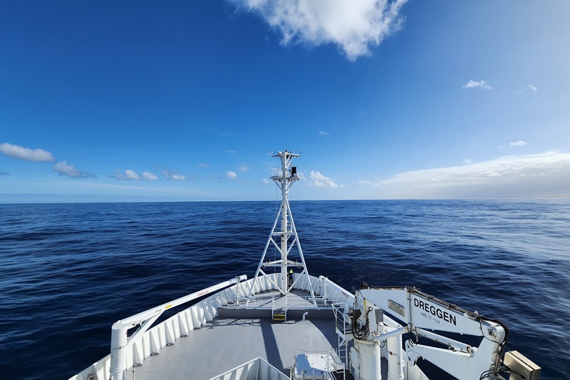 View of a ship's bow at sea with a clear blue horizon.