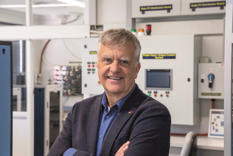 Dietmar Tourbier standing in a lab with his arms crossed facing and smiling at the camera