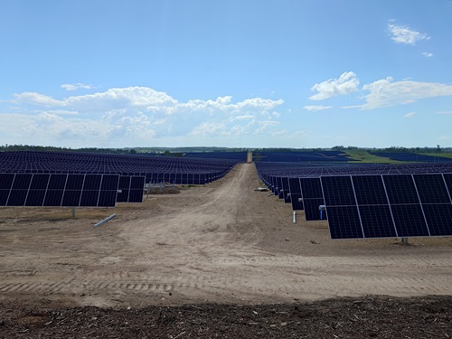 Solar panels in a field under a blue sky.