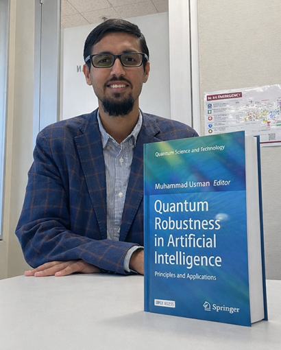 Man in a suit sitting with a book titled Quantum Robustness in Artificial Intelligence. 