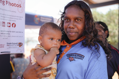 A mother smiling holding her small child.