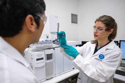 Two scientists in a lab looking at a sample, whilst wearing lab coats. 