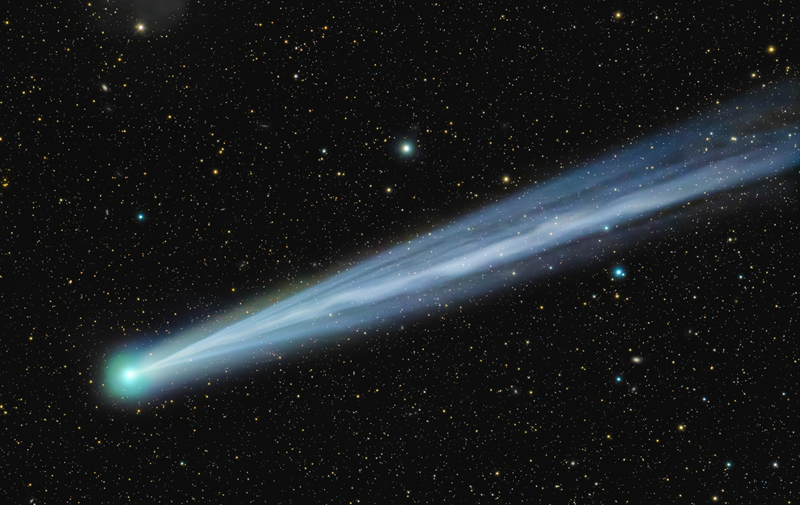 Photo of a comet in a big, vast starry sky.