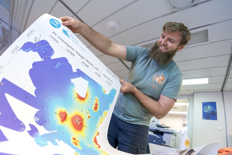 A person holding a colourful map that shows the seafloor.