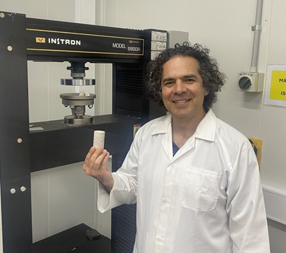 Scientist in white coat standing next to testing equipment in a laboratory