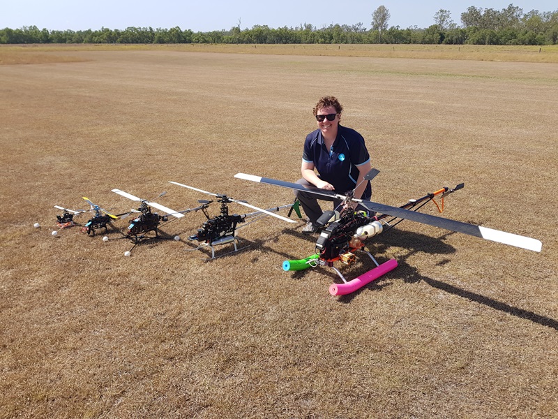 CSIRO's chief remote pilot in a dry field with 5 drones in a row from smallest to largest