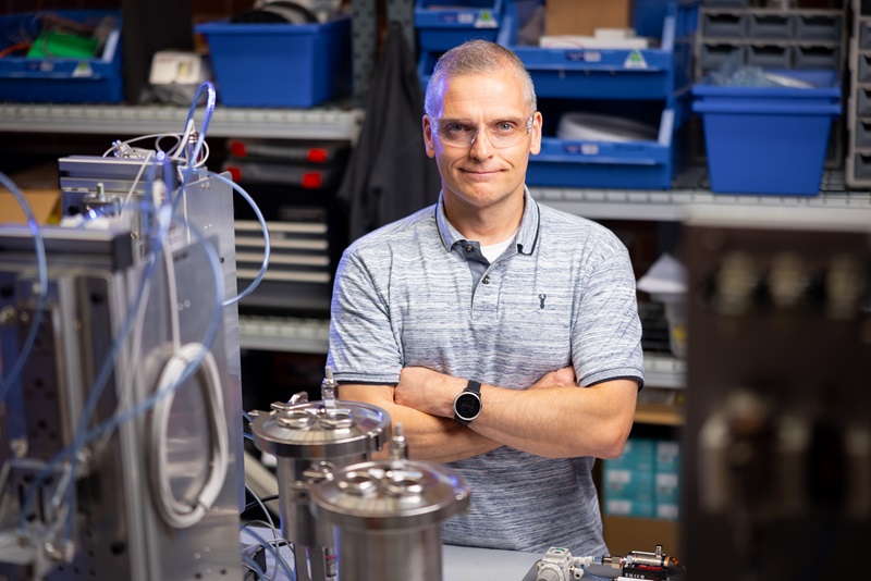 Man standing inside among boxes, wires and cylinders in a new lab being built 