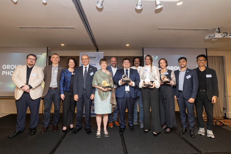 CSIRO representatives and fellow award recipients and attendees pose for a group photo at the 2026 ISGAN Awards, with four people holding trophies.