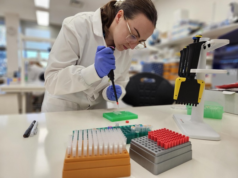 Researcher in a lab coat and protective gloves working with tuna samples in a lab