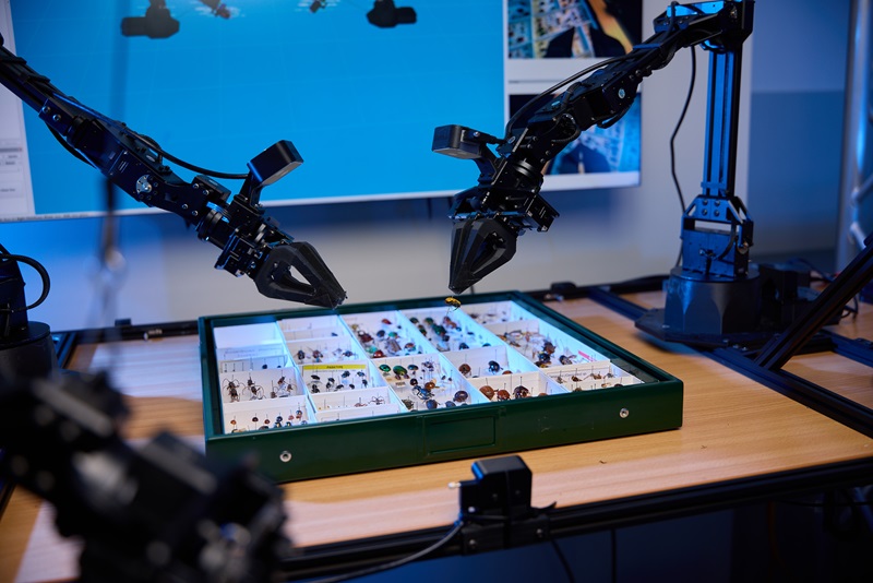 Robotic arms equipped with cameras and grippers sort and examine insect specimens in a laboratory setting.