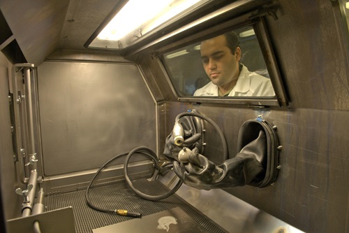 Image of a male researcher wearing a white lab coat and using 3D print lab machine to create a technical protoype