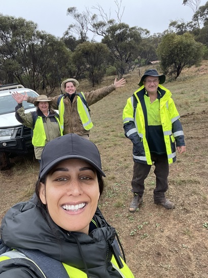 A group of four people outdoor on a research expedition. They are wearing yellow high-vis vests.