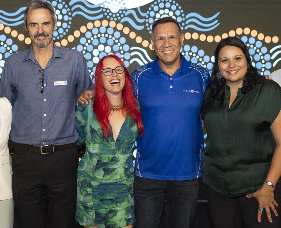 A mixed group of two men and two women standing next to each other smiling while posing for the camera.