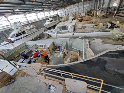 Two workers installing hybrid technology into the hull of a boat