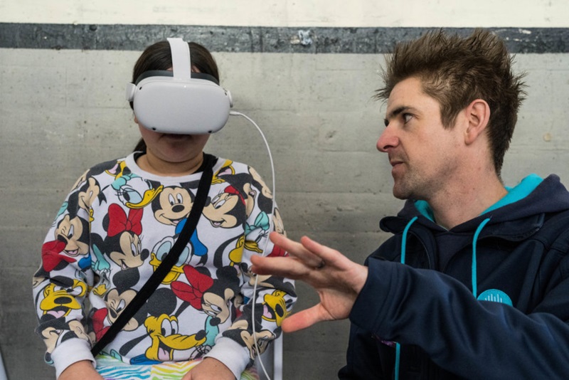A student getting an example of virtual work experience, wearing a VR headset while listening to instructions from a researcher.