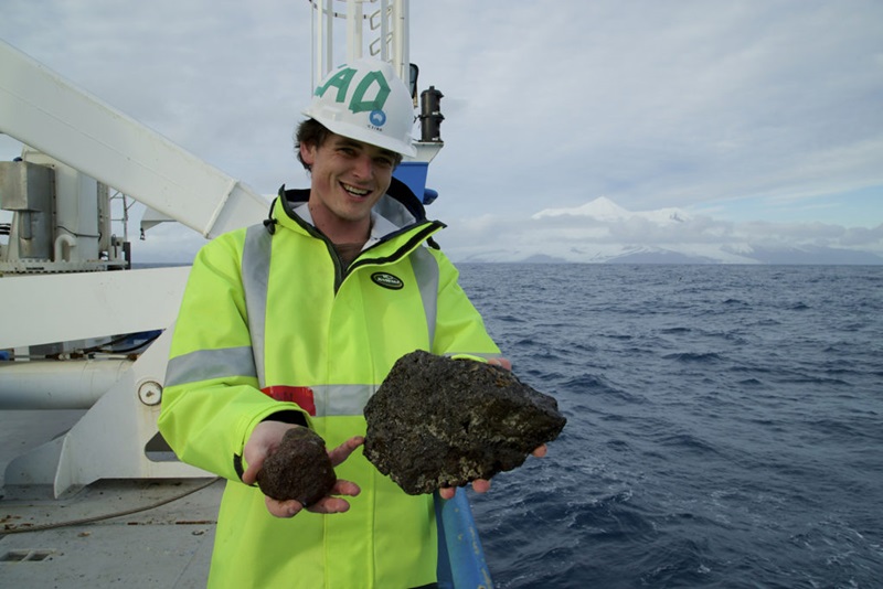 A person in hi-vis jacket on a ship in the ocean.