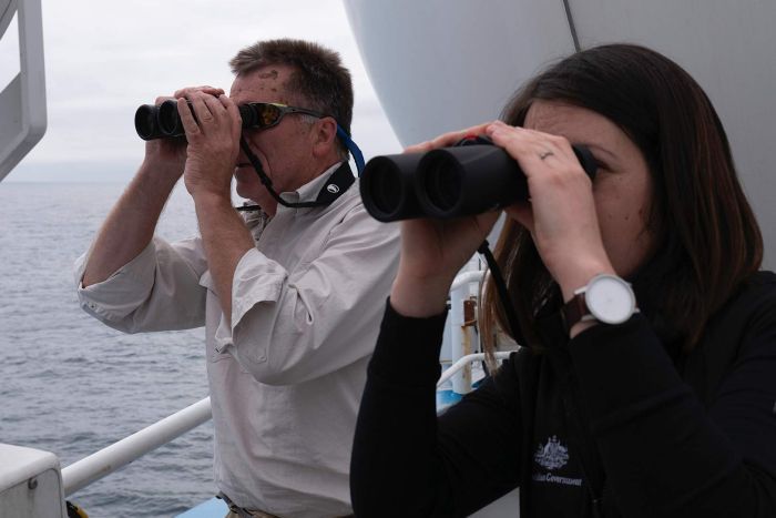 Dr Eric Woehler and Cassie Layton looking through binoculars