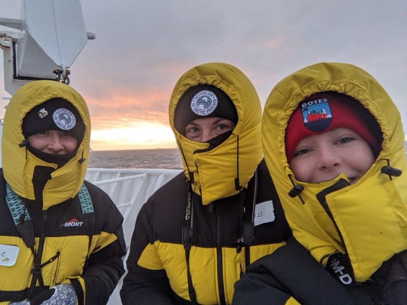 Three women in cold weather gear on a ship