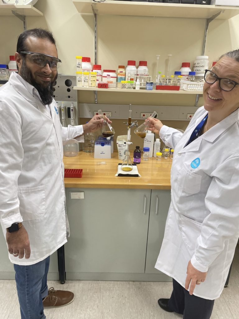 A photo of two people in white lab coats who are developing black seed oil