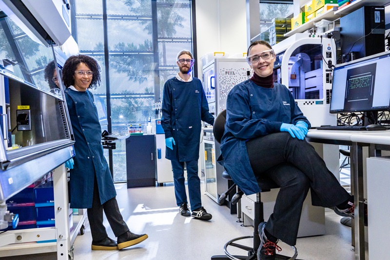 Synthetic biology team in lab gear smiling at camera
