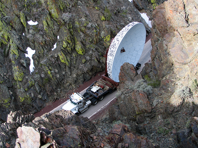 An aerial photo of part of a satellite being transported on a truck.